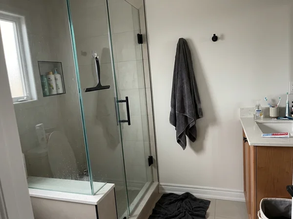 Custom frameless shower with matte black hardware in a Maple ensuite