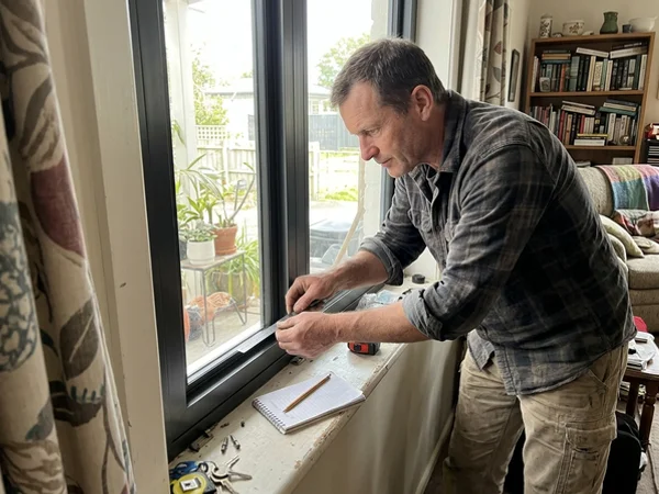 Glazier checking sash pocket depth with a steel rule