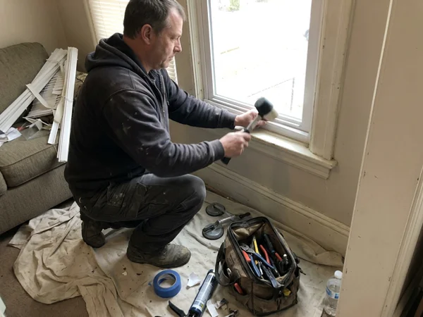 Glazier tapping the glazing bead back into a vinyl sash