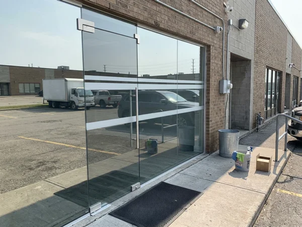New frameless entrance door with AODA markings at a Woodbridge unit