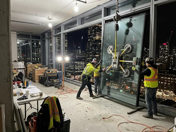 Night crew setting a curtain wall unit inside a Bay Street office