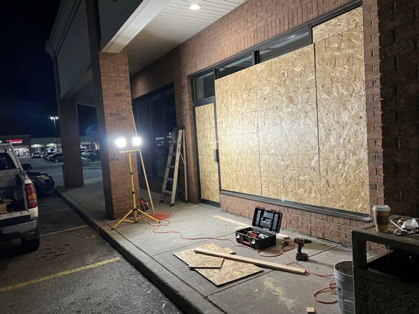 Plaza storefront boarded with OSB at night in Bramalea