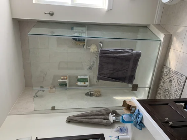 Repaired frameless shower with new brushed nickel hinges