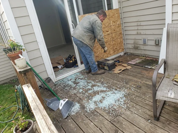 Shattered tempered patio glass with a temporary panel being fitted