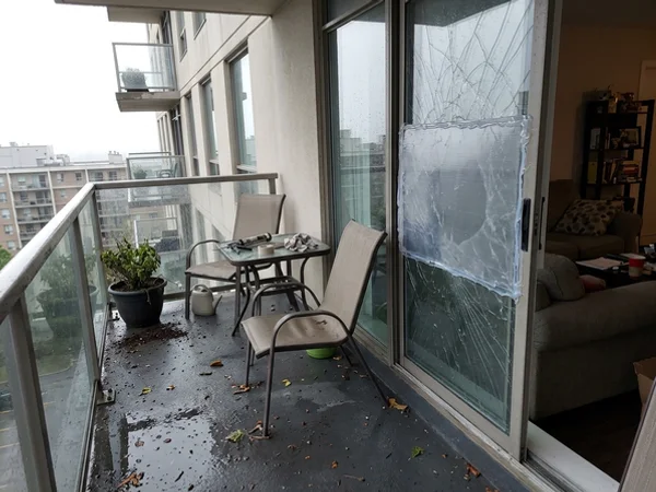 Storm-damaged condo balcony door secured with temporary polycarbonate