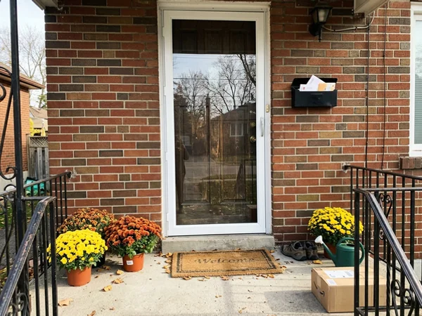 Storm door with a new tempered panel on a brick bungalow porch