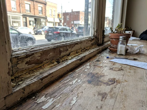 Failed silicone and water staining at a restaurant storefront sill on Ossington